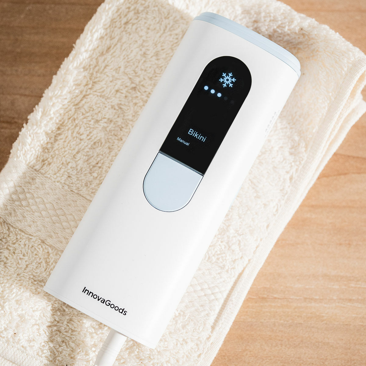 A close-up shot showing the digital display of the device with 'Bikini' mode activated, placed on a soft beige towel.