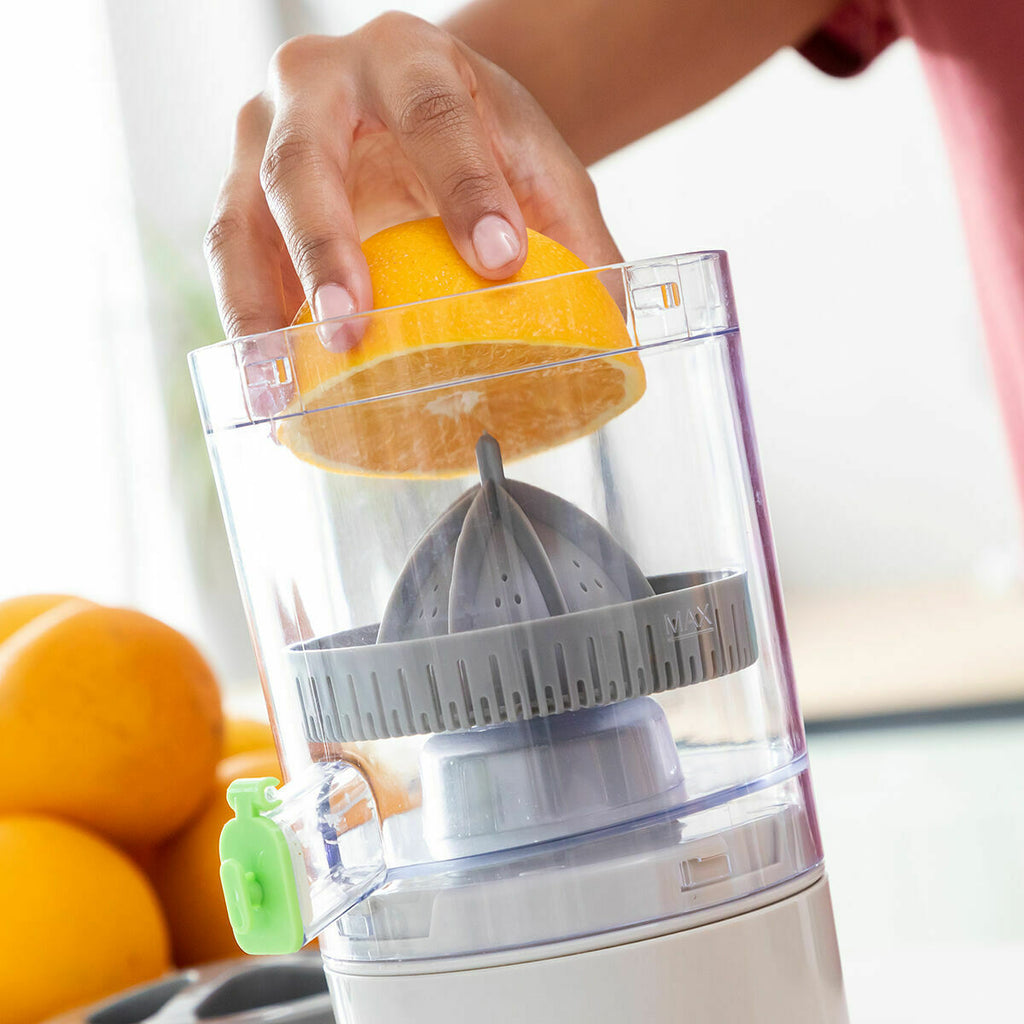 Close-up of an orange being placed into juicer by a hand.