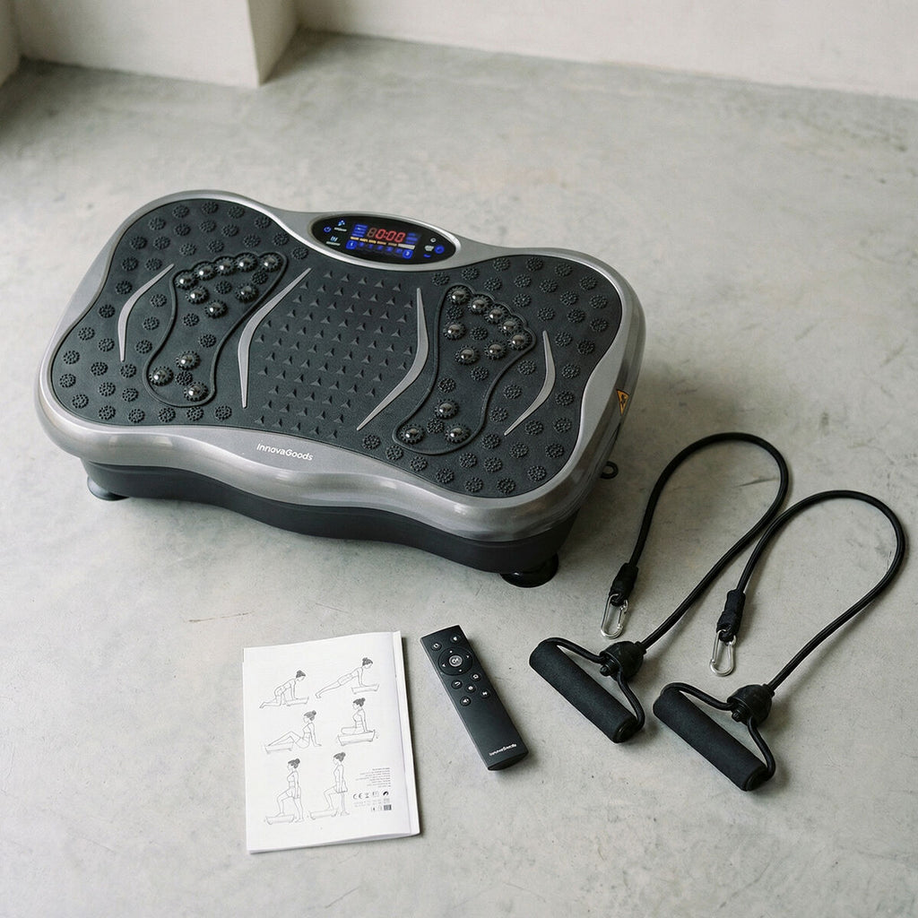 The vibration platform is shown with its accessories including resistance bands, remote control, and user manual on a concrete floor.
