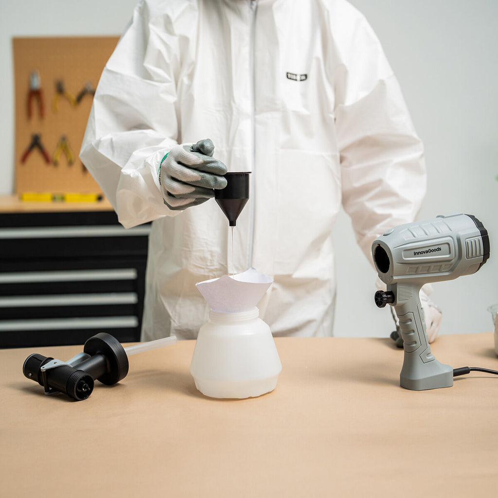 A person in protective gear prepares to use the sprayer by pouring paint into the container with a funnel, indicating preparation and ease of use.